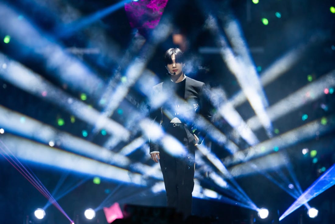 Taemin standing on KCON's stage awash in spotlights