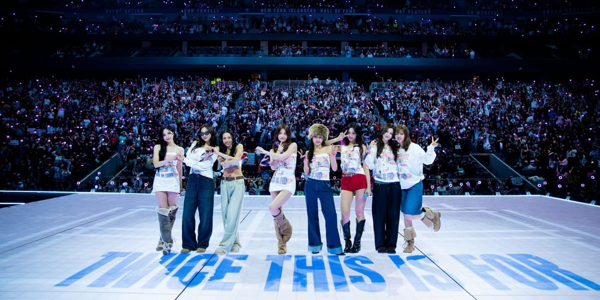 Twice posing on stage at Twice This Is For with a crowd of fans behind them